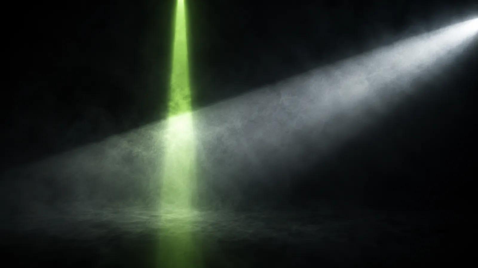 Two beams of light crossing in dark haze, one narrow and lime, the other broad and cold white