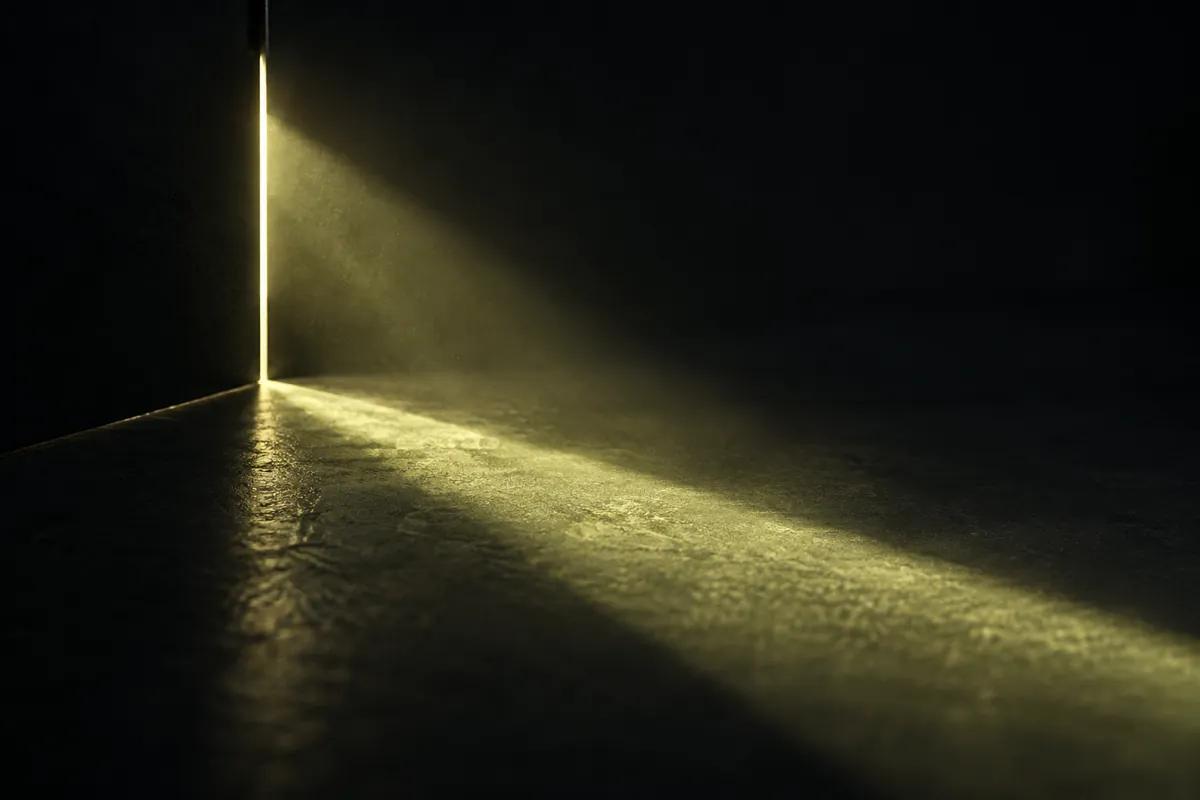 A narrow beam of lime light falling through a slit onto a dark surface