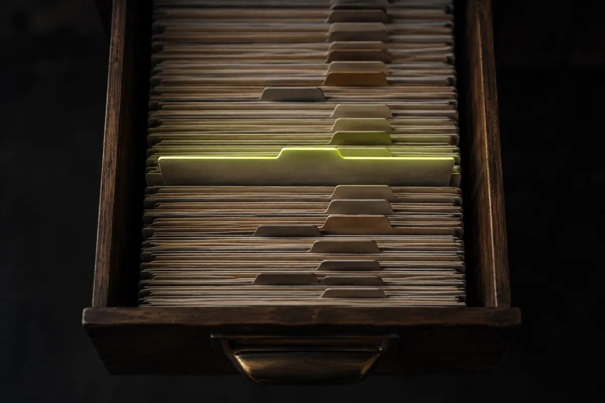 An index-card drawer seen from above, one card raised and edge-lit lime